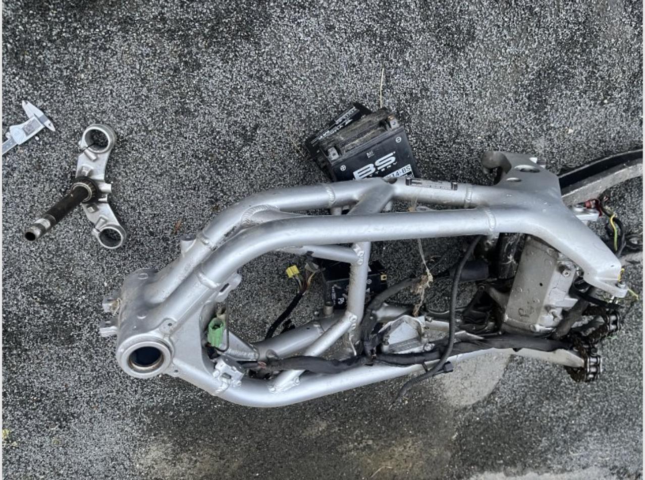 Cadre de moto démonté avec pièces d'axe et de roulement posées à côté